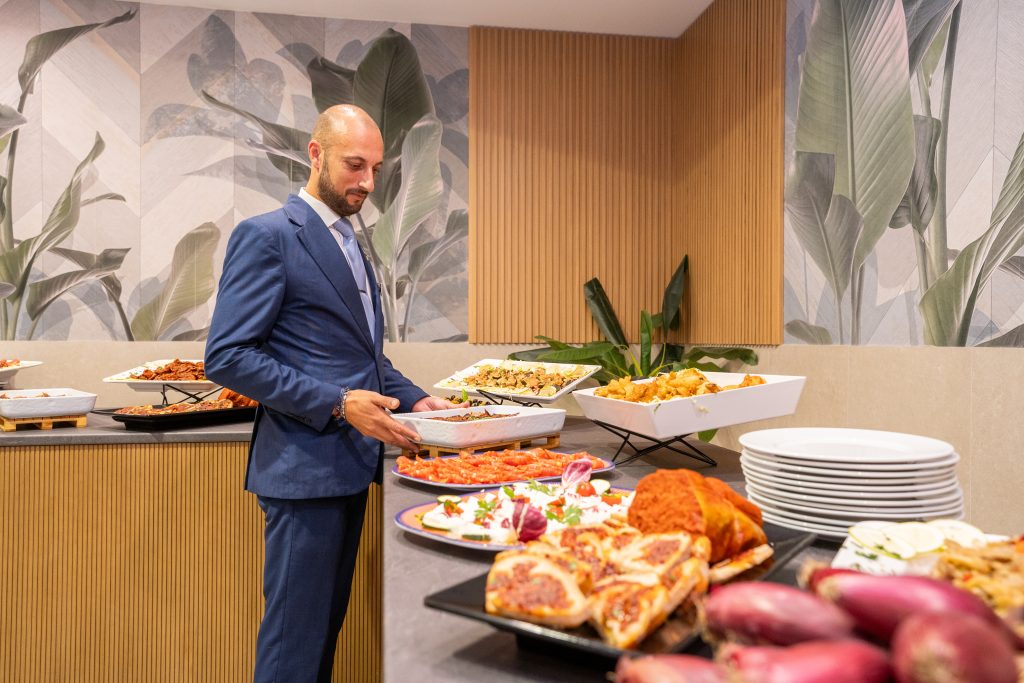 Il maître sistema i piatti al banco del buffet